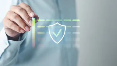 Hand using stylus to interact with digital shield icon and data chart.