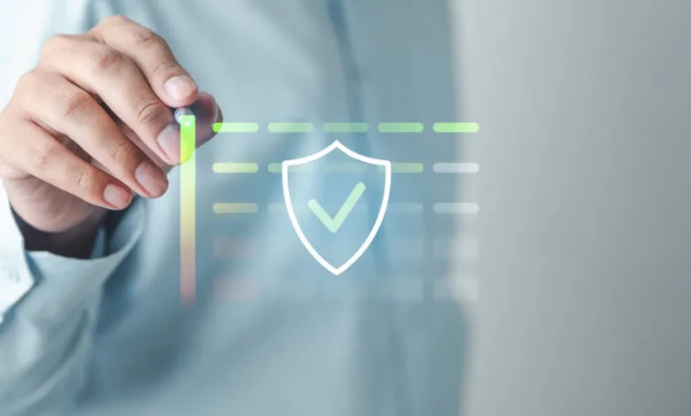Hand using stylus to interact with digital shield icon and data chart.