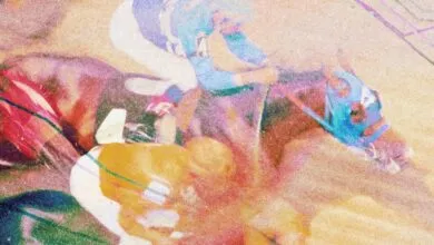 Abstract, grainy image of a horse race with jockeys in colorful attire.