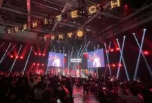Audience watches Koike Yuriko, Governor of Tokyo, on stage at event.