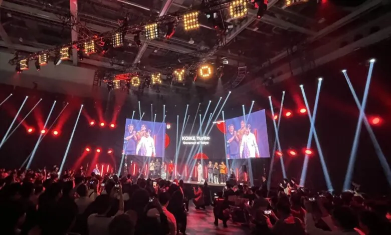 Audience watches Koike Yuriko, Governor of Tokyo, on stage at event.