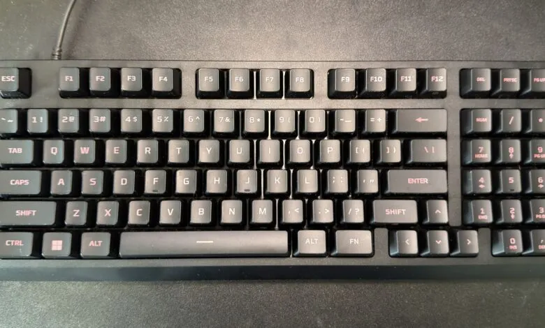 Black mechanical keyboard with red lettering on a dark surface.