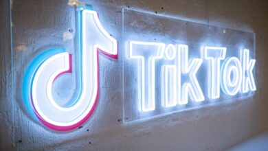 Illuminated TikTok logo sign with neon-style lighting on a textured wall.