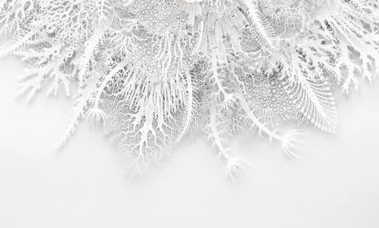 Intricate white paper cut art resembling coral or frost patterns.