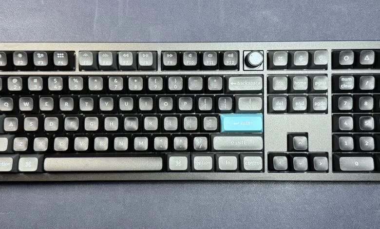 Gray mechanical keyboard with blue accent keys on a dark gray surface.