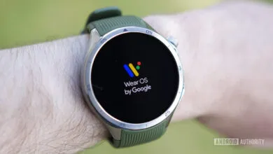 Wear OS smartwatch on wrist displaying the Wear OS by Google logo.