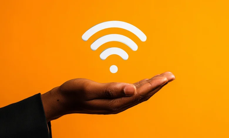 Hand holding a white WiFi symbol against an orange background.