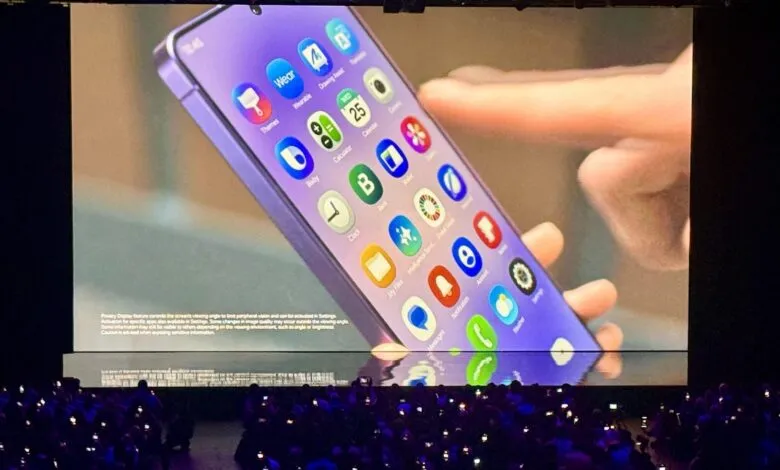 Large screen displays smartphone interface to audience at tech event.