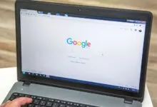 Laptop displaying Google search engine with a hand on the keyboard.