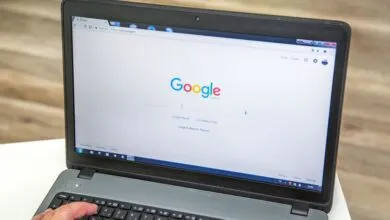 Laptop displaying Google search engine with a hand on the keyboard.