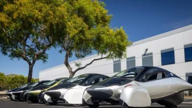 Line of Aptera solar electric vehicles parked outdoors on a sunny day.