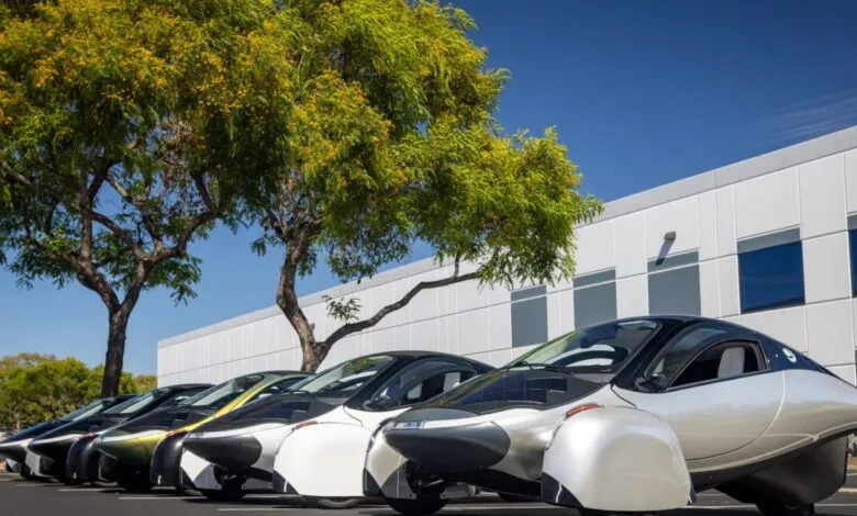 Line of Aptera solar electric vehicles parked outdoors on a sunny day.