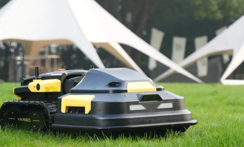 Black and yellow Yarbo robot lawnmower on green grass.