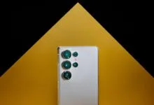 Silver smartphone with multiple camera lenses against a black and gold background.