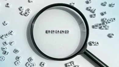 Magnifying glass focuses on 'BRAND' spelled with letter beads.