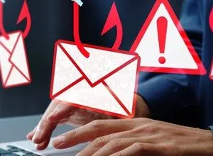 Hands typing on laptop with phishing email and warning icons overlaid.