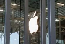 Apple logo illuminated on a modern glass building facade.