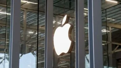Apple logo illuminated on a modern glass building facade.