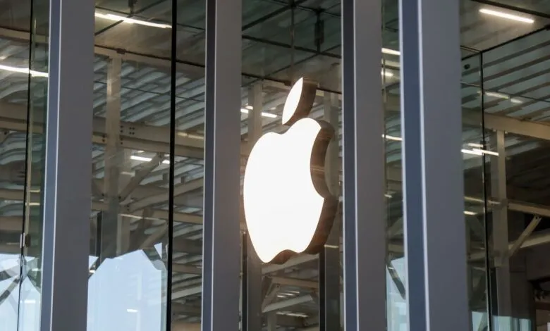 Apple logo illuminated on a modern glass building facade.
