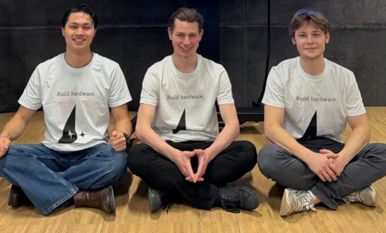 Three young men sit cross-legged wearing matching 'Build hardware' shirts.