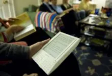 Person reading first-generation Kindle at book club meeting.