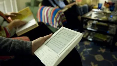 Person reading first-generation Kindle at book club meeting.