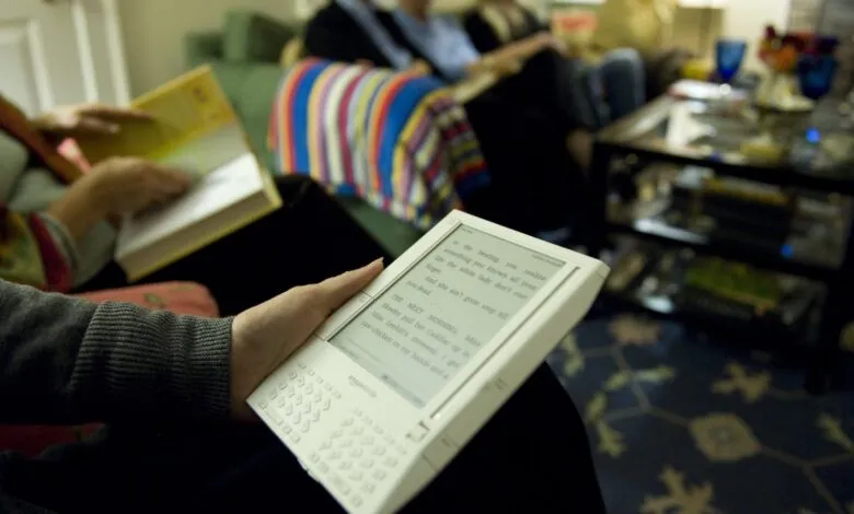 Person reading first-generation Kindle at book club meeting.