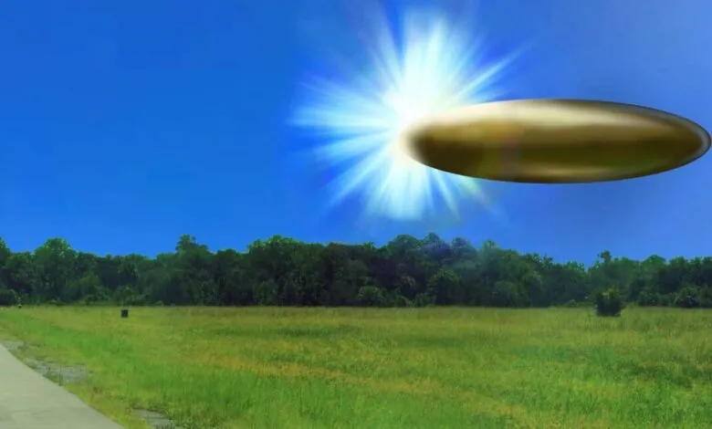 Gold UFO hovers over a green field under a bright blue sky.
