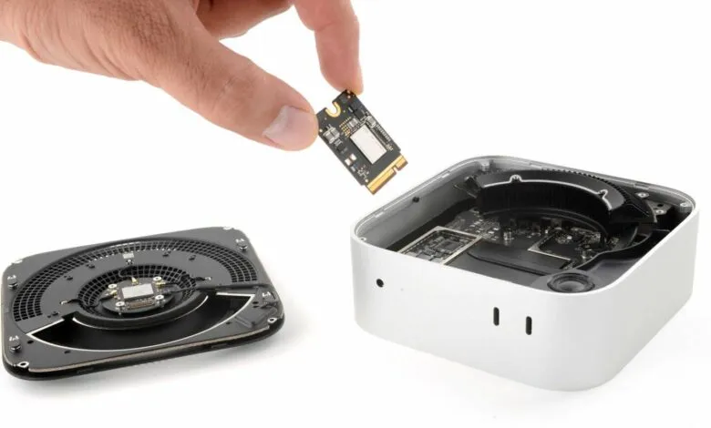 Disassembled Mac Mini showing internal components and hand holding a chip.