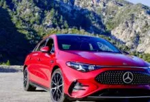 Red Mercedes CLA 350 parked on a road with a mountain backdrop.