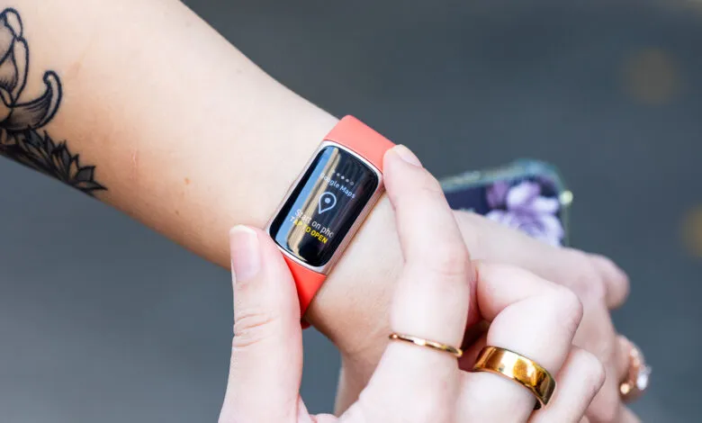 Person wearing a coral Fitbit Charge 6 showing Google Maps.