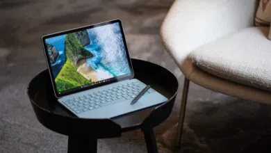 Surface Pro on a black table with a beach scene displayed on the screen.