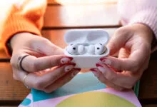 Hands holding open AirPods Pro case with earbuds inside.