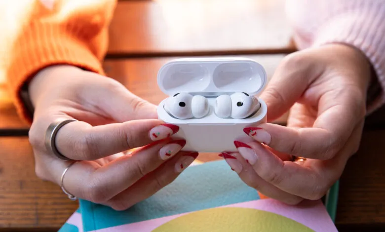 Hands holding open AirPods Pro case with earbuds inside.