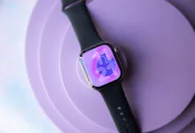 Apple Watch with black band displays 11:21 on a purple background.
