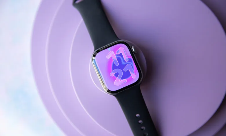 Apple Watch with black band displays 11:21 on a purple background.