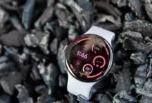 Google Pixel Watch with white band on dark textured background.