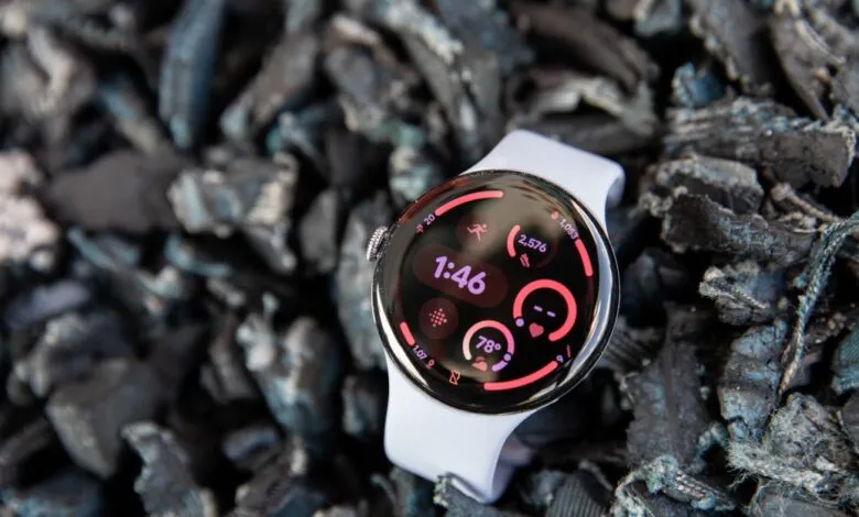 Google Pixel Watch with white band on dark textured background.