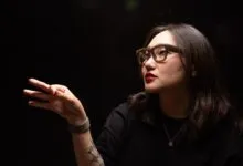 Woman wearing Ray-Ban Meta smart glasses gestures with three fingers.