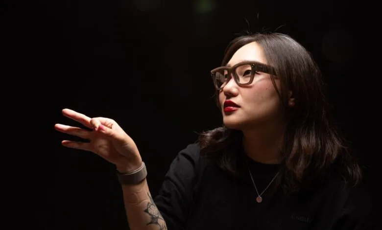 Woman wearing Ray-Ban Meta smart glasses gestures with three fingers.