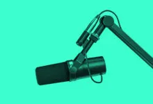 Studio microphone on boom arm against a vibrant teal background.