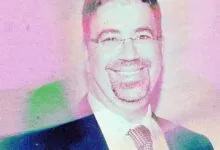 Smiling man with glasses and a beard, wearing a suit and tie.