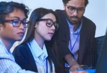 Three young professionals collaborate on a computer, focusing on the screen.