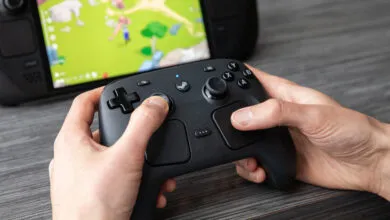 Hands hold a Steam Controller in front of a Steam Deck, playing a game.