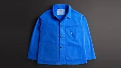 Bright blue chore coat with pockets and logo on a dark gray background.