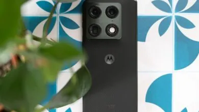 Close-up of a Motorola phone with a quad-camera system on a patterned surface.