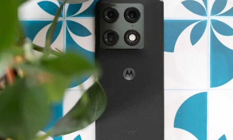 Close-up of a Motorola phone with a quad-camera system on a patterned surface.