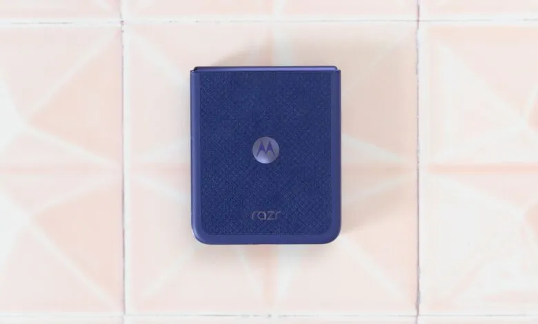 Closed Motorola Razr phone with textured blue back on tile surface.