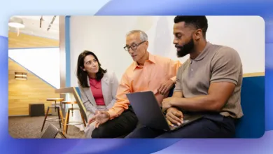 Three colleagues collaborate on a laptop in a modern office space.