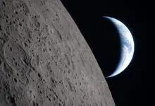 Crescent Earth rising over the lunar horizon, craters visible.